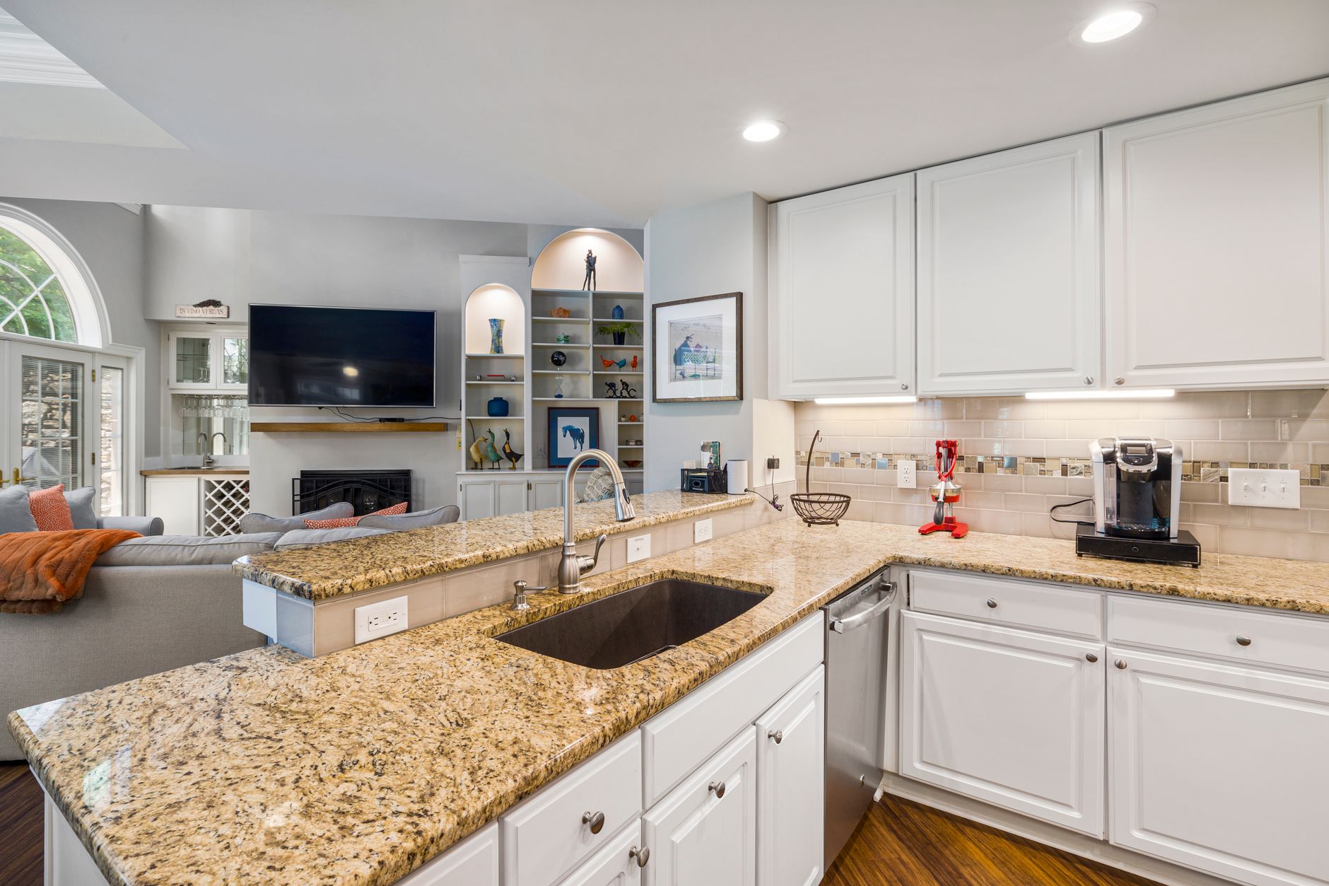 A modern kitchen with granite countertops opens into a stylish living room, featuring elegant furniture in Riverside, CA