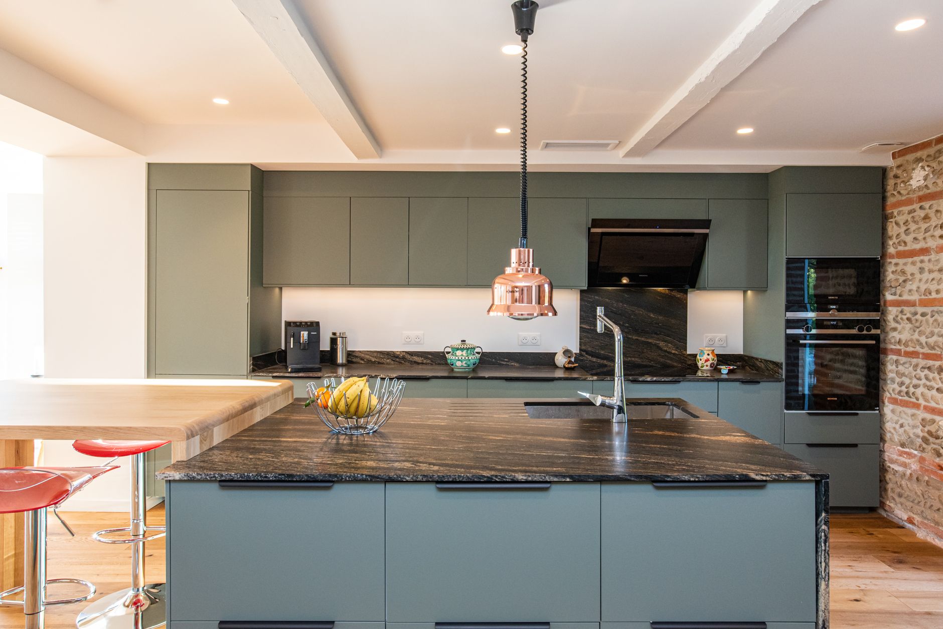 Contemporary kitchen design featuring green cabinets, marble countertops, and a copper pendant light in Riverside, CA