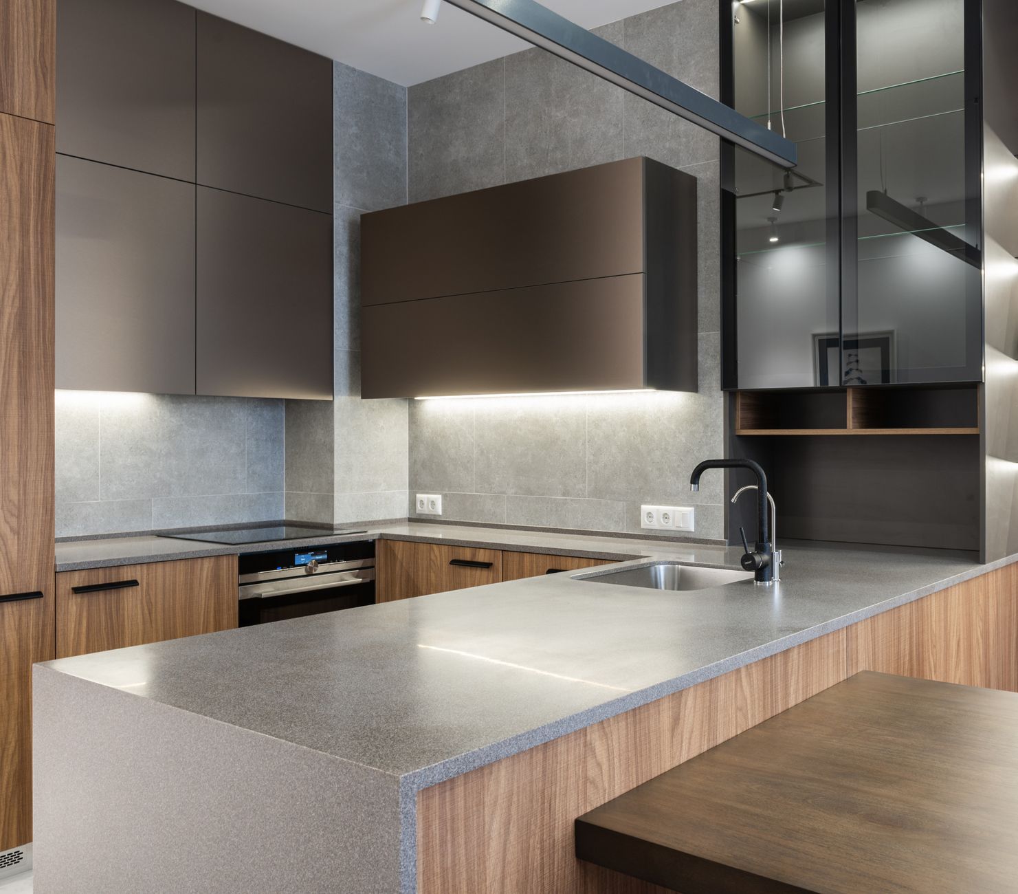 Interior of modern kitchen with faucet on gray counter and cupboards with illumination near electric in Riverside, CA