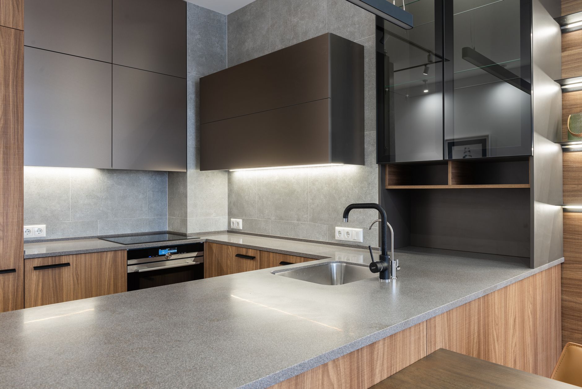 Interior of contemporary gray kitchen counter with sink and faucet placed near wooden cupboards and stove in Riverside, CA