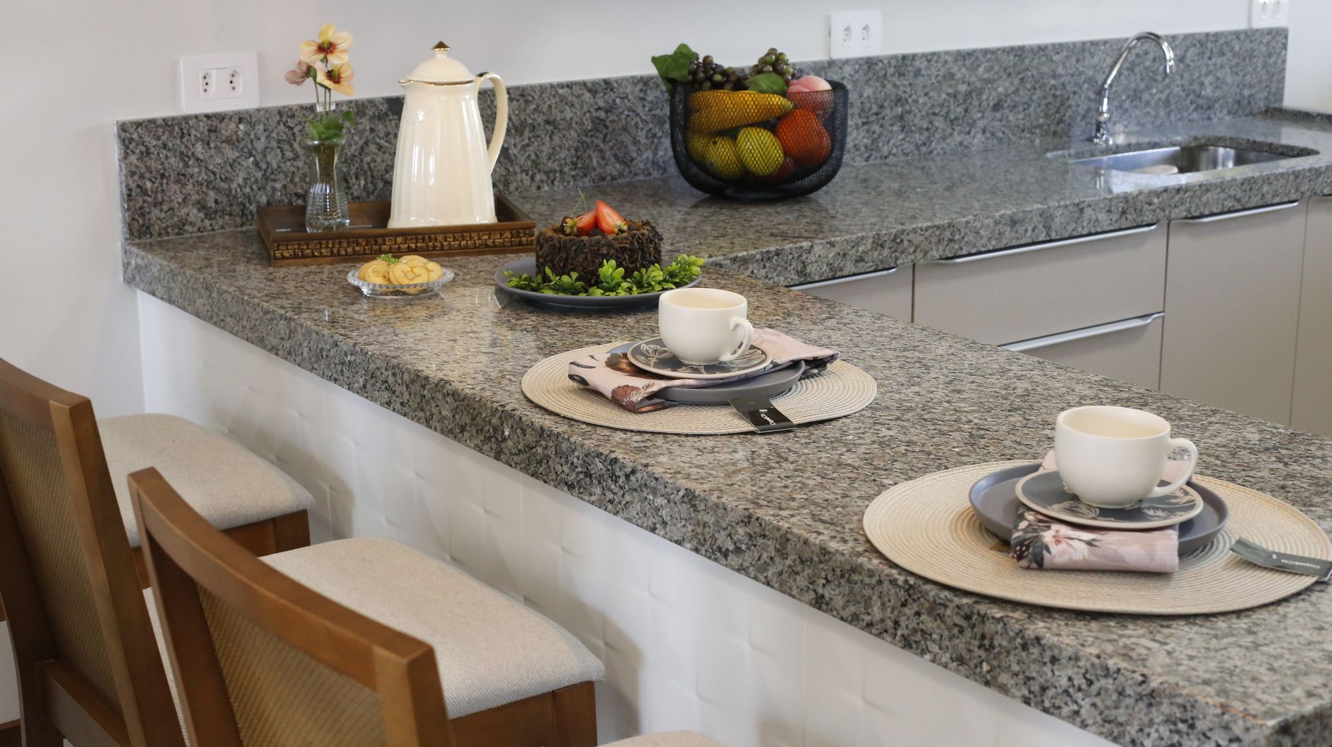 A cozy kitchen counter setup with two places set for breakfast, featuring cups and a cake in Riverside, CA